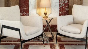 A room with two armchairs, a marble wall, and a lamp.