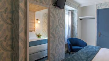 Una camera d'albergo con un letto, una sedia, una televisione a parete e una porta.