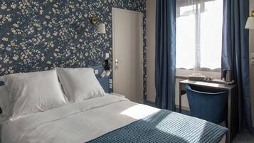 Een hotelkamer met een bed, een bureau en een raam met gordijnen.