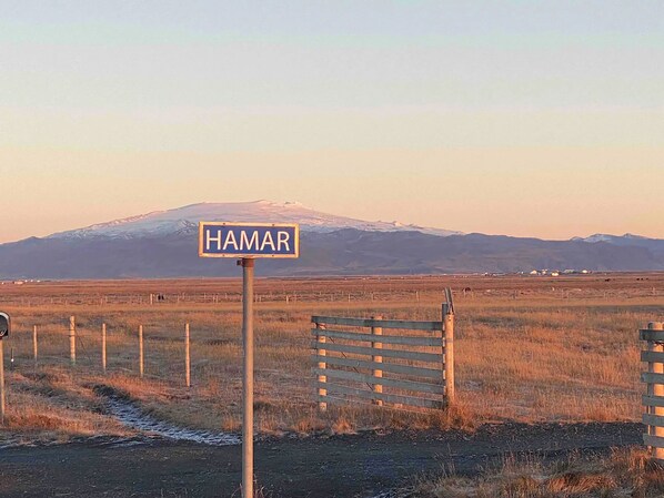 Señal que dice 'HAMAR' en un entorno rural con una montaña al fondo.