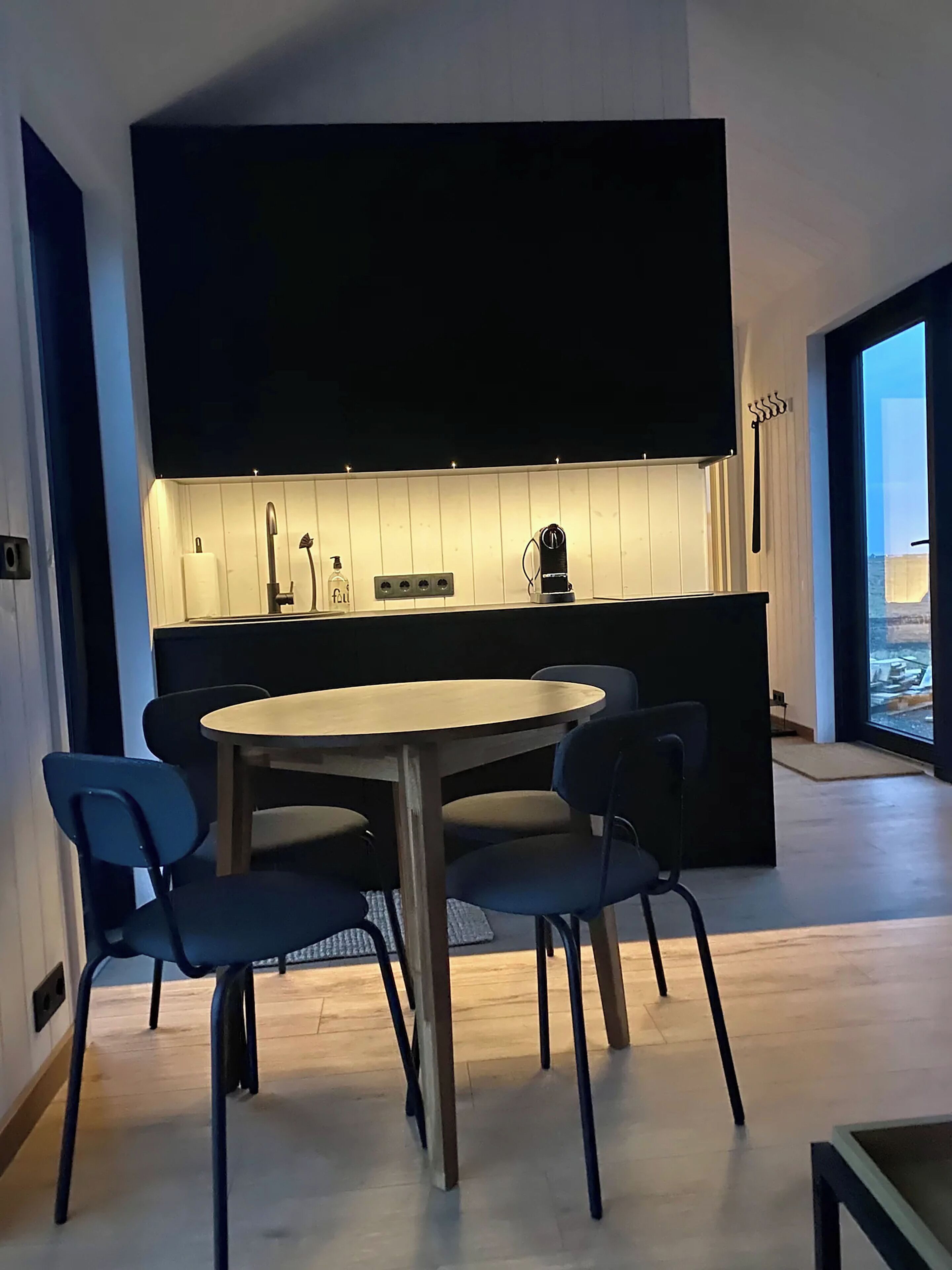Una cocina moderna con una isla central, una mesa redonda con sillas y un amplio ventanal con vistas.