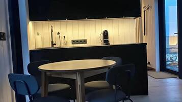 Una cocina moderna con una isla central, una mesa redonda con sillas y un amplio ventanal con vistas.