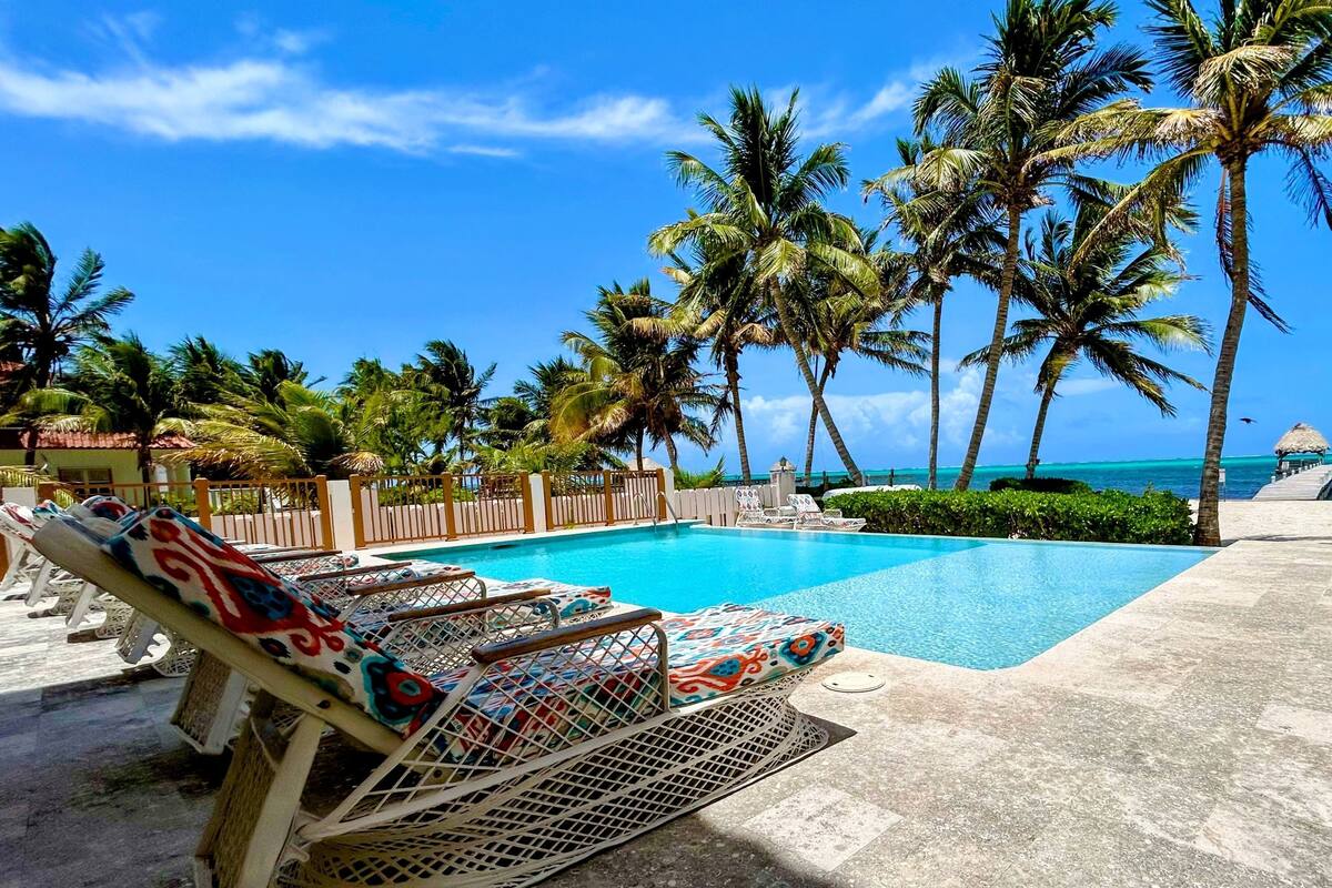 A poolside area with lounge chairs and a view of the ocean.
