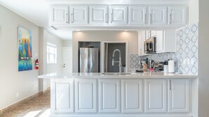 A modern kitchen with white cabinetry, a stainless steel refrigerator, and a built-in microwave. - Miramar Villas Resort (San Pedro)