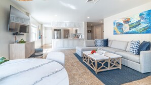 A modern living room with a marble coffee table, grey sofa, and a kitchen in the background. - Miramar Villas Resort (San Pedro)