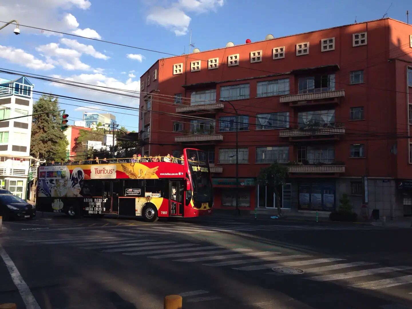 A red double-decker bus with advertisements on the side, parked at a street intersection.