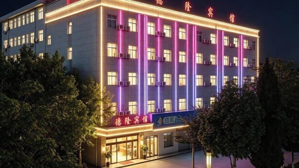 A multi-story hotel with a modern facade, illuminated signage, and a flat roof. - Delong Hotel(Fufeng County Hospital Fufeng Bus Station Branch) (Fufeng County)
