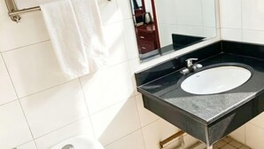 A bathroom with a black sink, white tiles, a towel rack, and a toilet. - Delong Hotel(Fufeng County Hospital Fufeng Bus Station Branch) (Fufeng County)