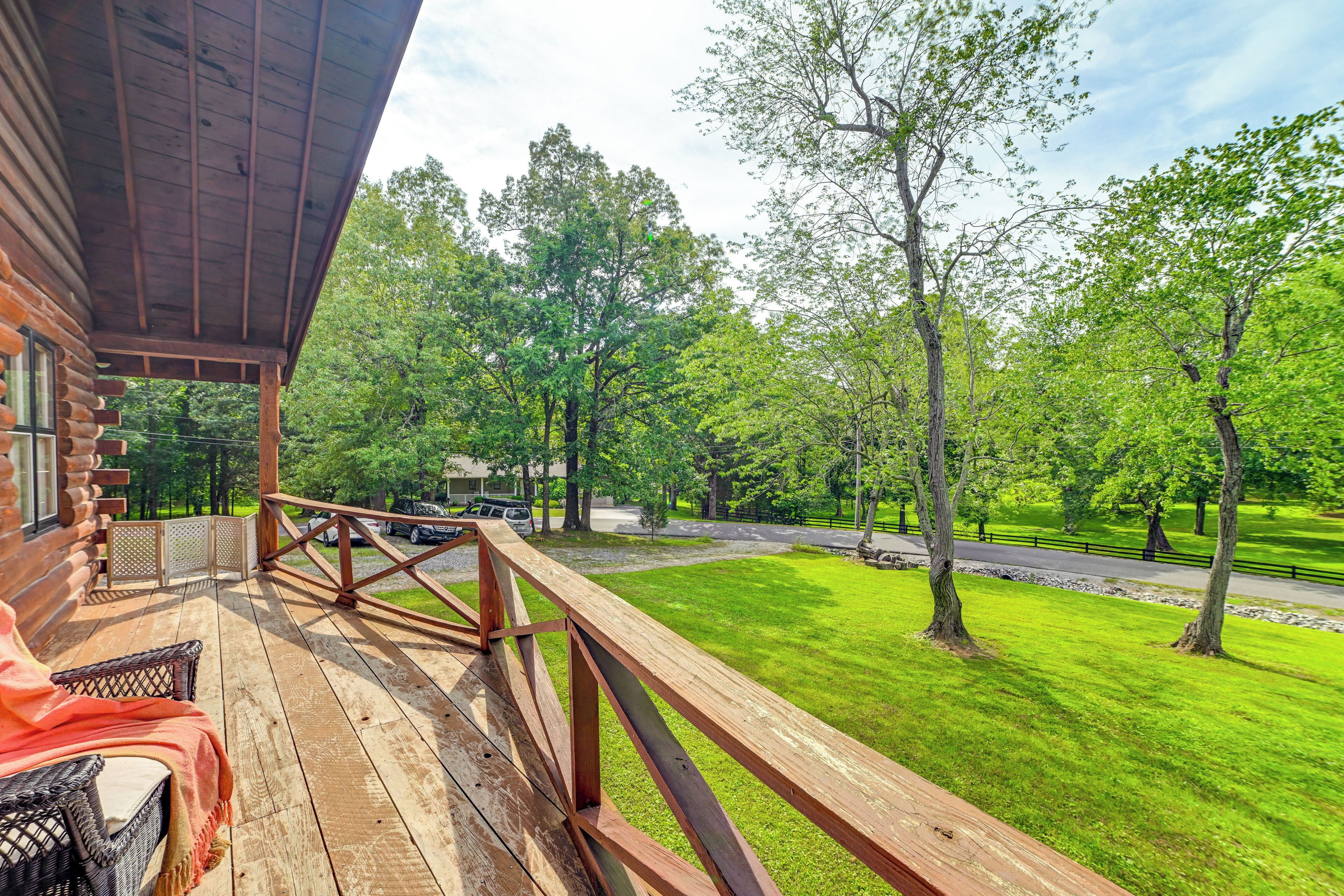 A wooden deck with a view of a green lawn and trees.