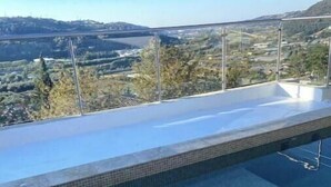 A rooftop infinity pool with a clear view of the surrounding landscape.