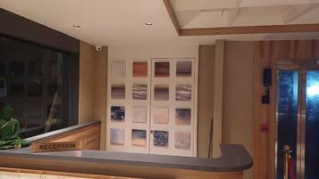 A reception area with a wooden reception desk, a Buddha statue, and a wall with framed artwork.
