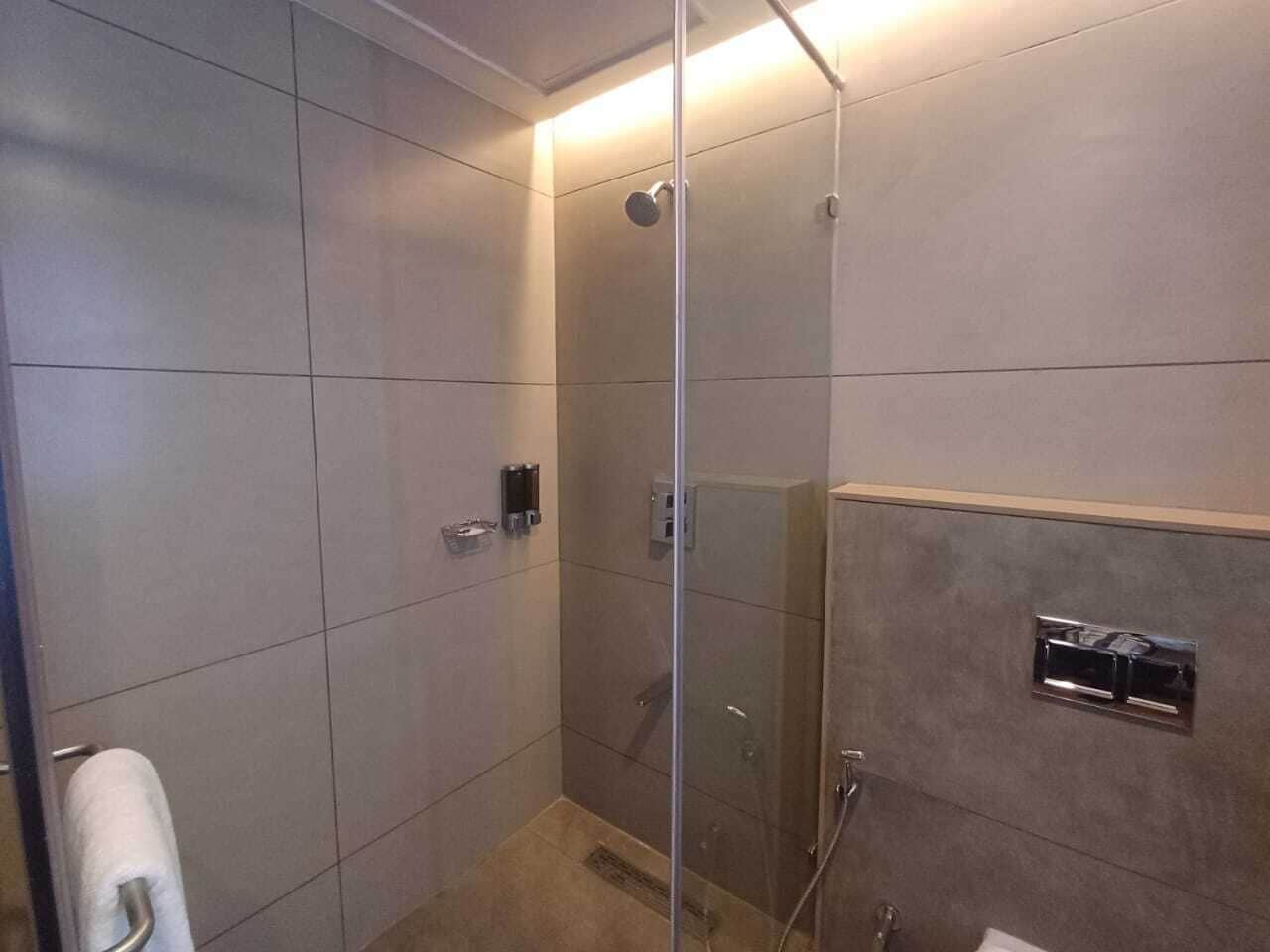 Un baño moderno con cabina de ducha de vidrio, inodoro y lavabo con grifo de cromo.