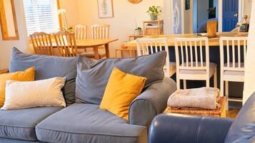 A living room with a sectional sofa, a dining table, and chairs.