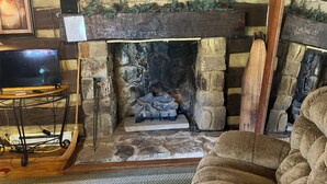 A cozy living room with a stone fireplace, a television on a wooden stand, and a comfortable armchair. - Historic, cozy cabin at Headley Inn Winery & Vineyard with WiFi, AC & Fireplace (Zanesville)