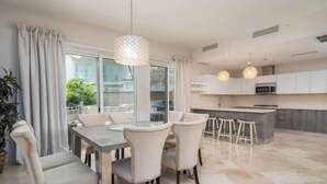 Une cuisine moderne avec des meubles blancs, un îlot central et des luminaires suspendus.