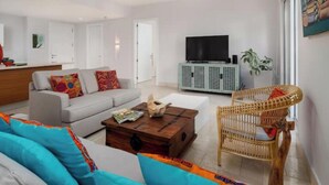 Een moderne woonkamer met een bank, salontafel en een rieten fauteuil.