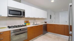 Een moderne keuken met witte kasten, een roestvrijstalen magnetron, een gasfornuis en houten werkbladen.