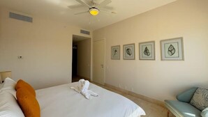Une chambre d’hôtel avec un lit, un ventilateur de plafond et des œuvres d’art encadrées accrochées au mur.