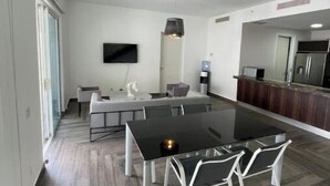 A modern kitchen with a dining area, featuring a black dining table, white chairs, and a TV mounted on the wall. - Family-Friendly 3BR Beachfront Puntarena (Rio Hato)
