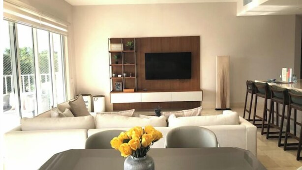 Ein modernes Wohnzimmer mit einer Couch, einem Couchtisch und einem an der Wand befestigten Fernseher.