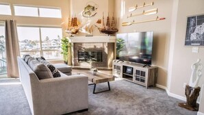 Een woonkamer met een bank, salontafel, televisie, open haard en decoratieve objecten.