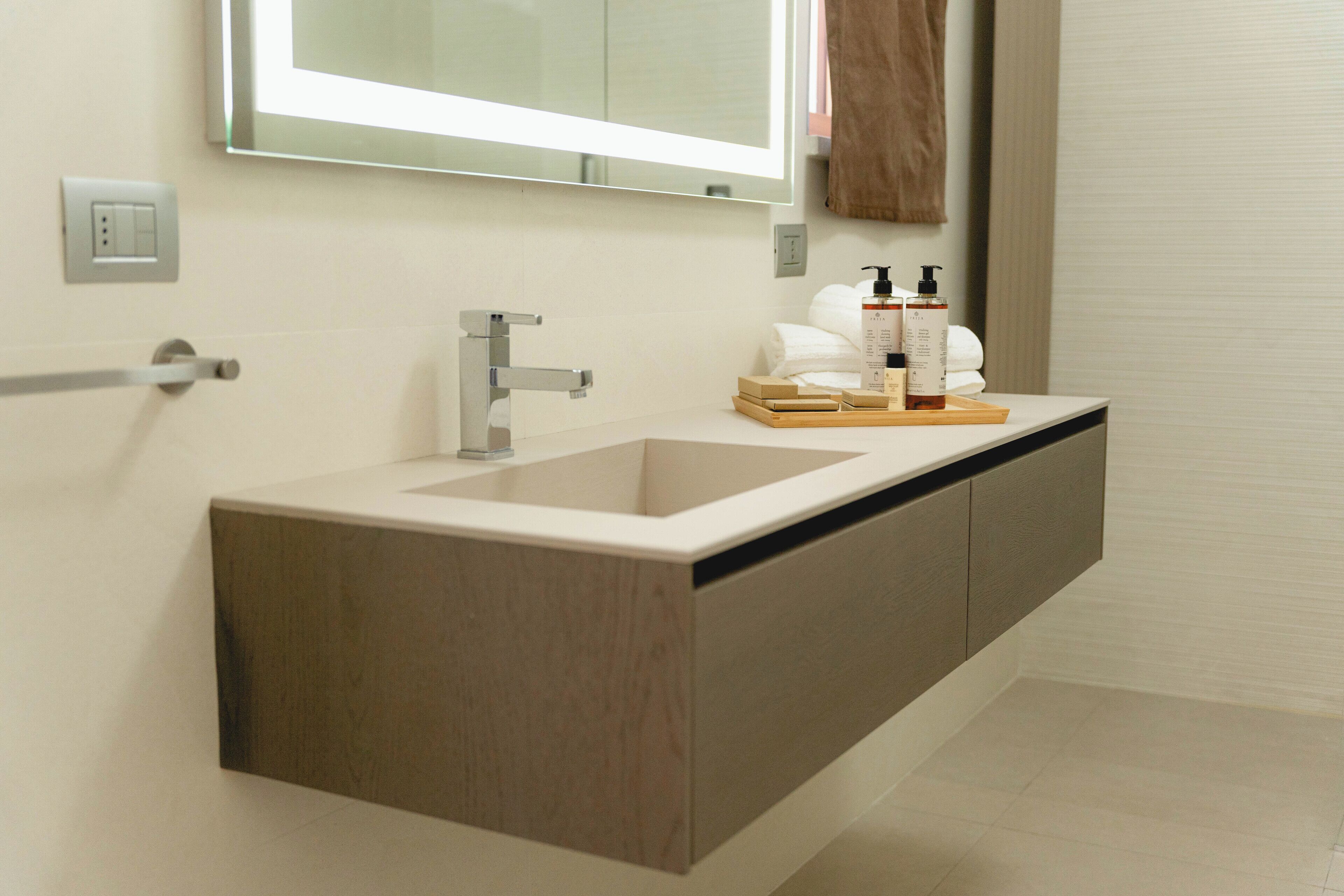 A modern bathroom with a large sink, a mirror, and a wooden vanity.