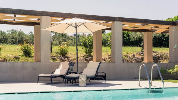 A pool area with lounge chairs and a pergola. - Ayma B&B (Mirabella Eclano)