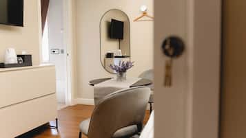 A hotel room with a bed, a bedside table, a TV, a mirror, and a door.