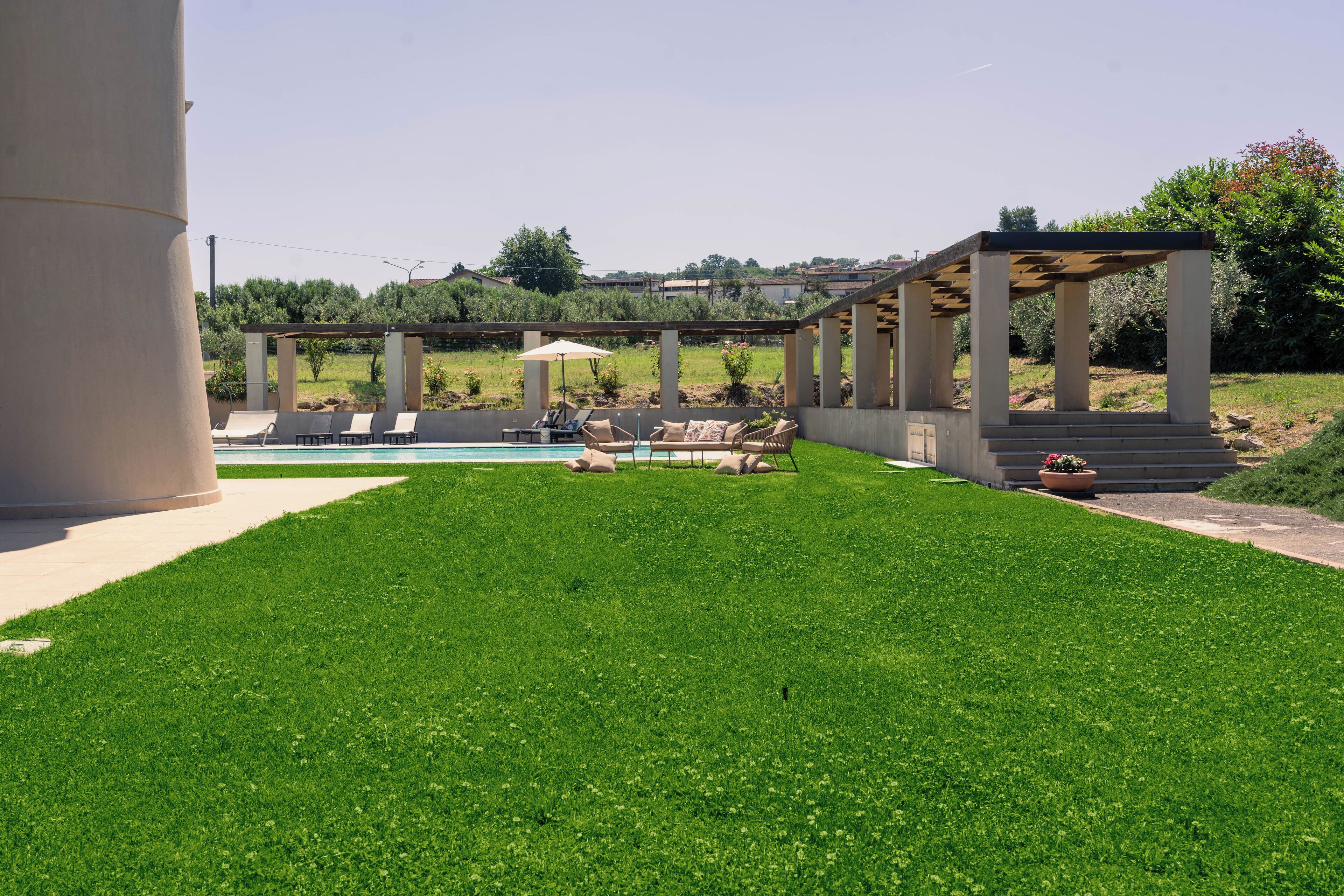 Ein gepflegter Außenbereich mit Schwimmbecken, Liegestühlen und einer Pergola.