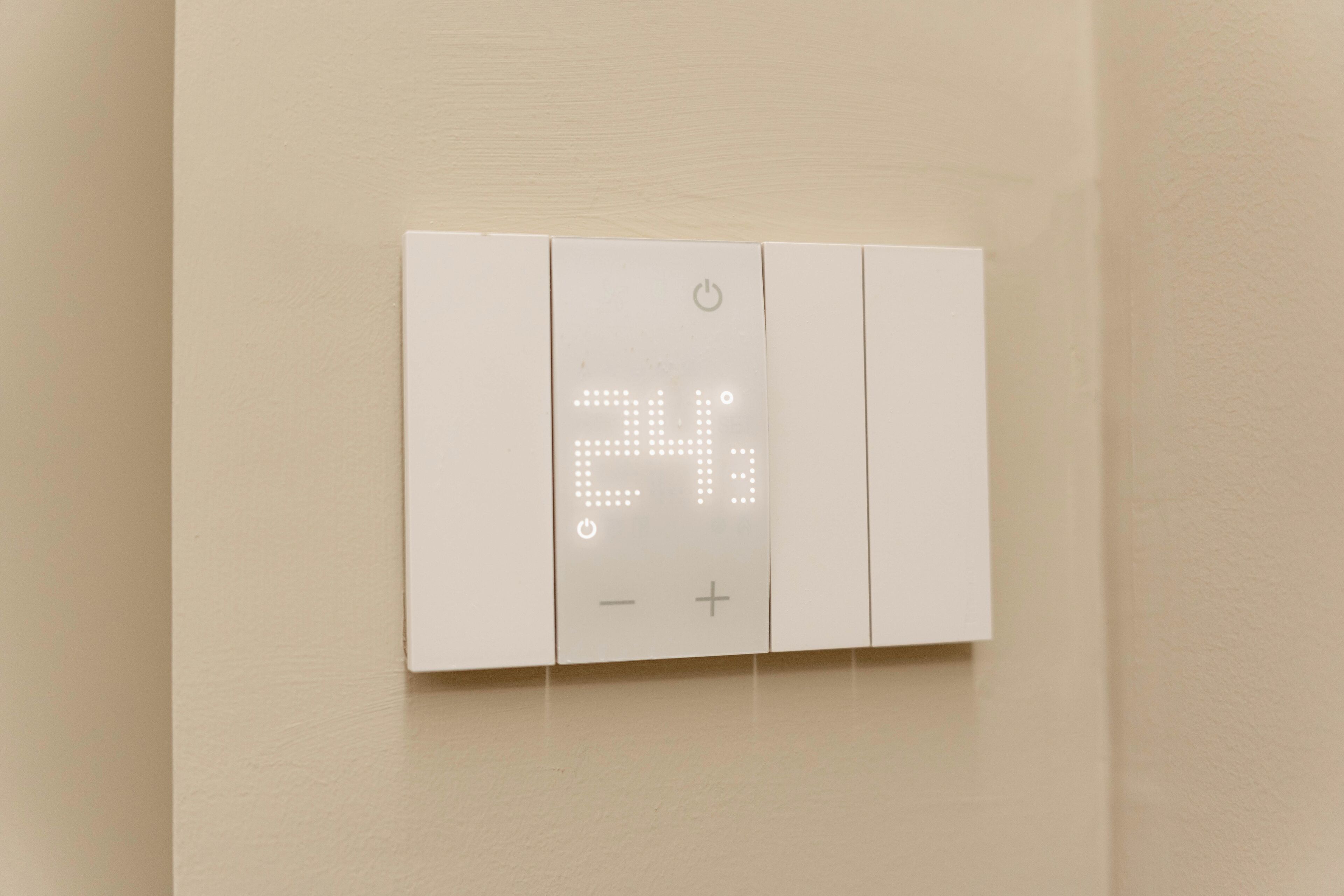 A thermostat with a digital display on a wall.