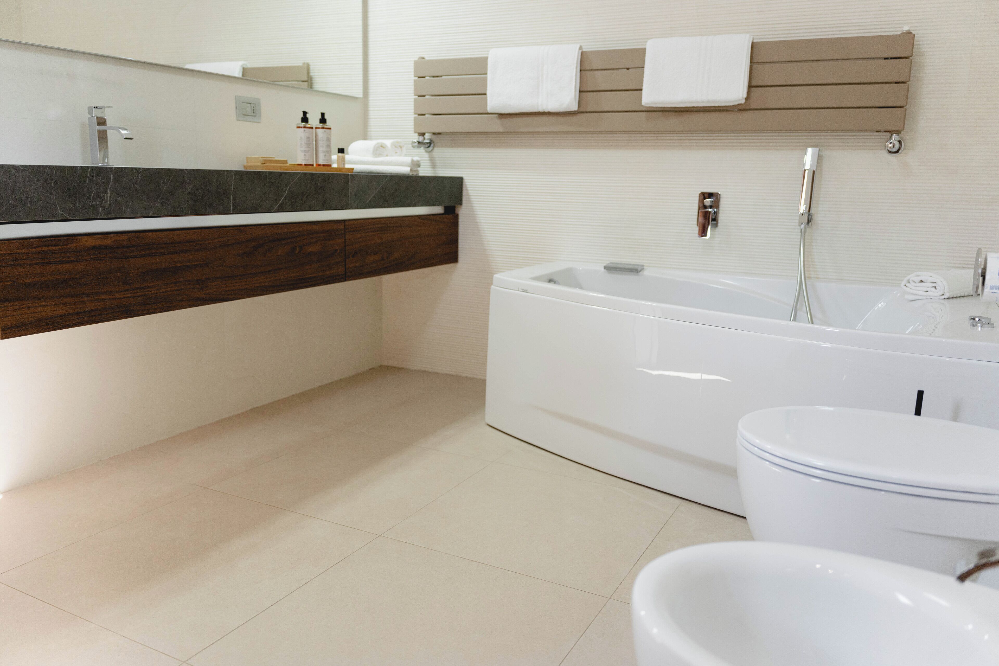 A modern bathroom with a large bathtub, a toilet, and a vanity with a mirror.