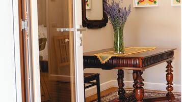 Una habitación con una mesa de madera, un florero con flores, un espejo y obras de arte en la pared.