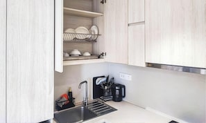 A modern kitchen with a built-in sink, a coffee maker, and a dish rack.