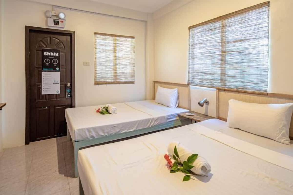 A hotel room with two beds, a door with a 'Shhh!' sign, and two windows with blinds.