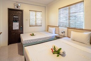 Una camera d'albergo con due letti, una porta con il segnale 'Shhh!' e due finestre con tende.