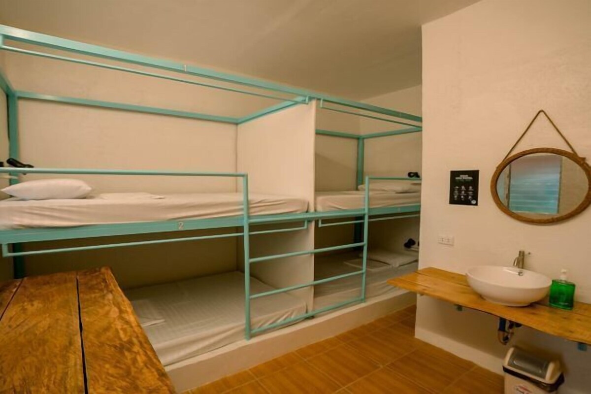 A bunk bed room with a wooden table, a sink, and a mirror on the wall.