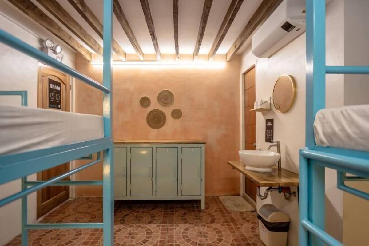 A bunk room with a bunk bed, a cabinet, a sink, and a mirror.