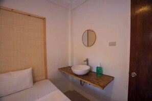 A bedroom with a bed, a wooden shelf with a sink and a mirror, and a door. - Mad Monkey Panglao (Panglao Municipality)