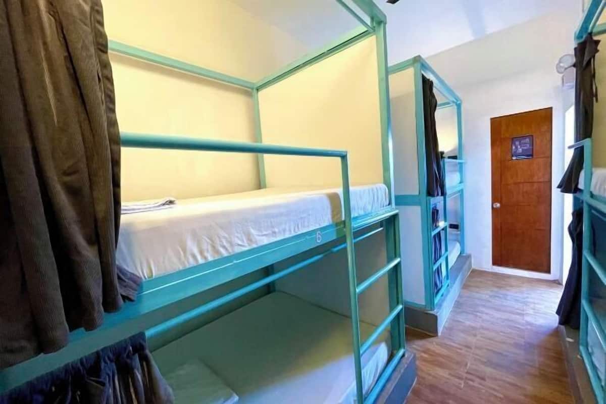 A bunk bed room with a wooden door and a shelf with items.