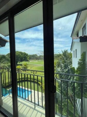 Enjoy a view of the pool and surrounding landscape from this balcony with a glass door.