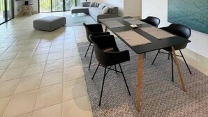 Un vaste espace de vie comprenant une grande table à manger, des sièges confortables et une vue sur un balcon.