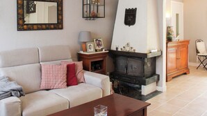 Una sala de estar con chimenea, un sofá con cojines estampados, una mesa de centro y un espejo en la pared.