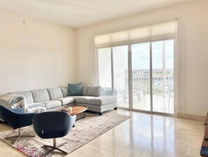 Relax in this stylish living room with a large sofa, armchair, and city view.