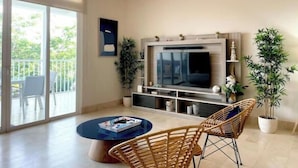 Een moderne woonkamer met een grote flatscreen televisie, een ronde salontafel, rieten stoelen en een balkon met tuinmeubilair.
