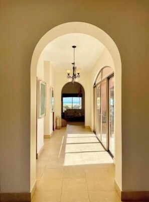 Stunning hallway leads to a spacious living area with a high ceiling and large window.