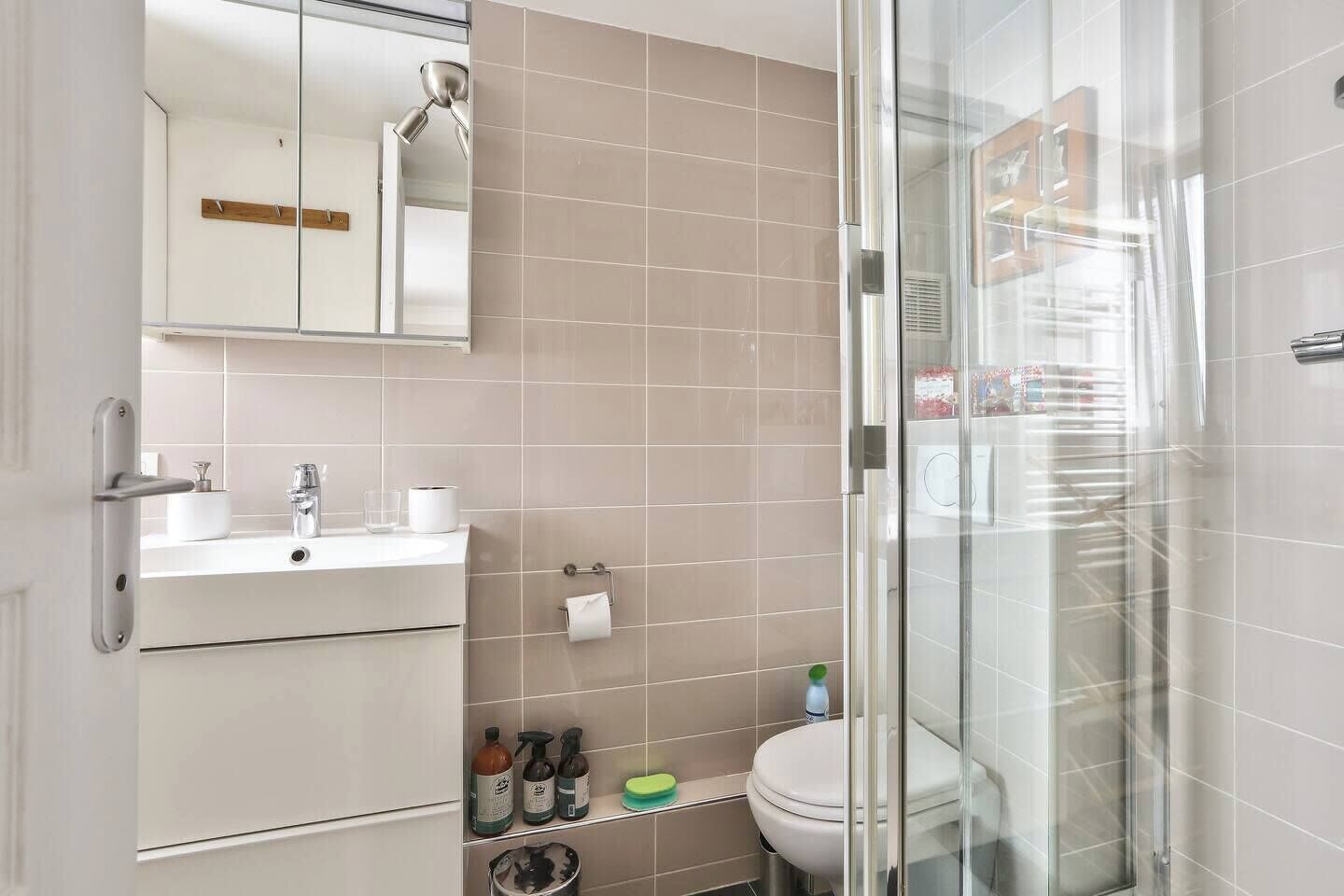 Une salle de bain moderne avec une douche à parois de verre, un lavabo avec un miroir et des toilettes.