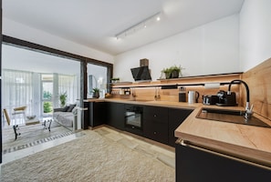 Cozinha moderna com bancada de madeira, armários pretos e forno embutido.