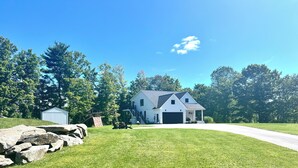 A single-story house with a garage, a small shed, and a stone wall. - Cozy sunlit apartment steps from downtown Dover. Parking included (Rollinsford)