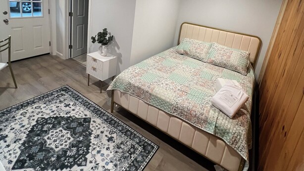 A bedroom with a bed, a nightstand, a chair, a door, and a window. - More then a Motel With Garden , Renovated Rooms at heart of Boothbay (Boothbay)