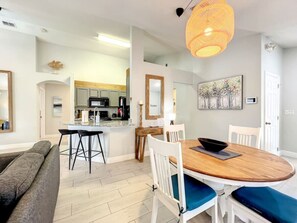 Relax in this stylish living space with a central dining area, comfortable sofa, and modern kitchen.